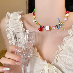 Close-up of beaded choker necklace with cherry and star charms on a model's neck