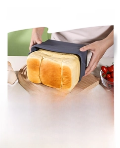 Silicone bread mold with freshly baked loaf on wooden board with kitchen accessories