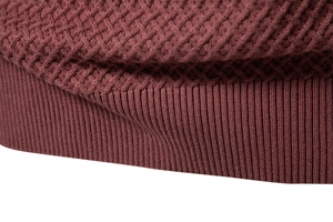 Macro detail of wine red knit sweater with waffle texture and ribbed cuff finishing
