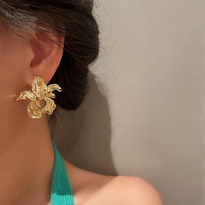Macro detail of large gold flower earring with artistic irregular petal texture