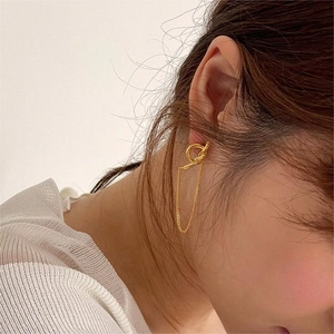 Close-up of a minimalist gold knot earring and ear thread on model, sleek elegant jewelry