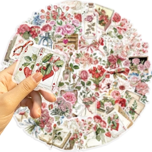 Detail of vintage floral and Ace of Hearts stickers held by hand for scrapbooking