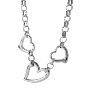 Close-up of three polished silver heart-shaped pendants on a textured cable chain necklace