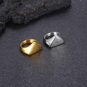 Macro detail of polished gold and silver stainless steel geometric rings on dark rock
