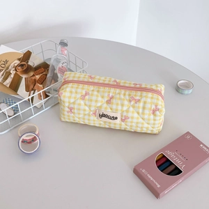 Detail of yellow checkered quilted pencil case with pink bow embroidery and zipper