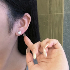 Close-up of teardrop zircon sterling silver stud earrings worn on a female ear model