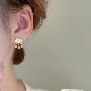 Macro shot of gold cloud earrings with dangling zircon water drops on female ear