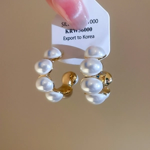 Detail of C-shaped gold-plated silver earrings with elegant white pearls and price tag