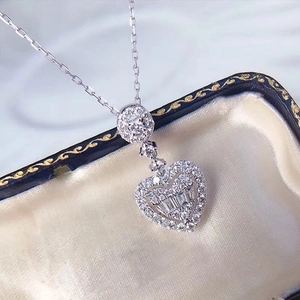 Elegant heart-shaped diamond pendant necklace with step-cut stones on a vintage jewelry box