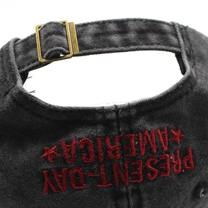 Dettaglio della fibbia in metallo e ricamo rosso sul cappello di jeans lavato