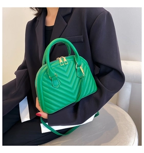 Detail of green quilted leather shell bag with gold hardware and V-stitch pattern