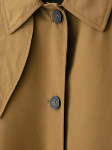 Detail of khaki trench coat featuring matte buttons and premium twill fabric texture