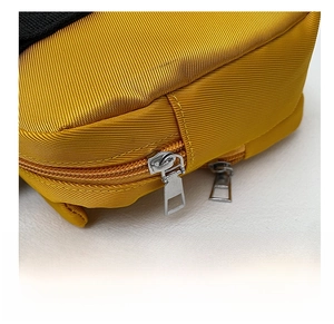 Detalle de bolso de nailon amarillo con cremalleras dobles de metal plateado y costuras