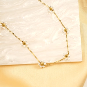 Elegant gold flower necklace with pearls on a silk and marble surface, 45-degree angle