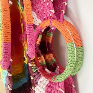 Close-up of handmade rainbow woven straw tote showing colorful patchwork and round handles