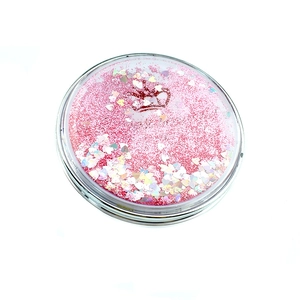 Détail d'un miroir de poche rose pailleté avec motif couronne et effet sable mouvant