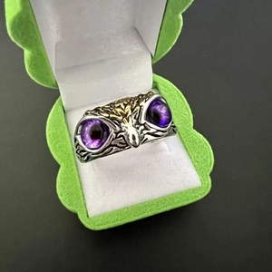 Macro detail of owl ring with purple gem eyes and gold accents in a jewelry box