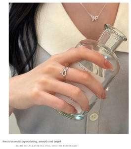 Close-up of elegant silver bow ring on finger with refined minimalist metal texture