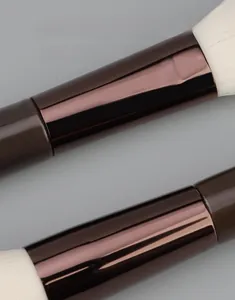 Detailopname van de dikke bruine aluminium buis en zachte witte haren van make-up kwasten