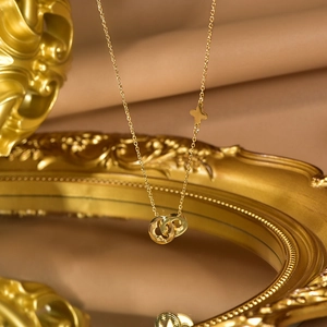 Detail of gold double-ring pendant with CD cutout letters and star flower engraving