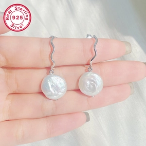 Detail of S925 sterling silver C-shaped earrings with baroque pearls on white silk cloth
