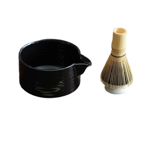 Japanese Matcha whisk set with black ceramic bowl and bamboo whisk on a white stand