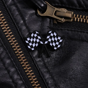 Close-up of checkered racing flag enamel pin on black leather background with zipper