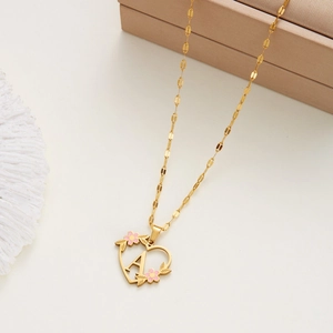 Detail of gold heart pendant featuring pink floral accents and a central letter A charm