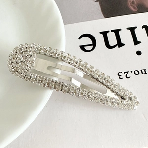 Detailed view of shimmering silver spindle hair clip with rhinestones on a white plate