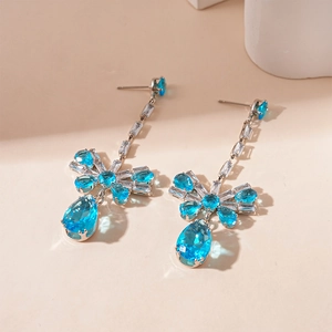 Detail of silver bow earrings with drop-shaped blue zircon and faceted crystals