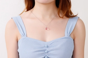 Detail of a pink faceted crystal pendant on a delicate silver chain worn by a woman