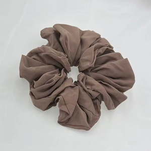 Detailed close-up of a brown chiffon scrunchie with soft elastic texture and rich pleats