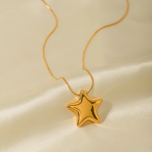 Close-up of 18K gold star pendant necklace on beige satin fabric with soft lighting