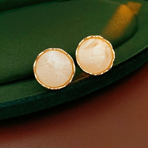 Macro shot of French vintage round earrings with cream texture and gold metal frame