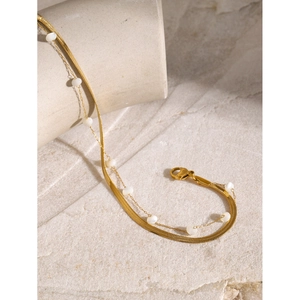 Elegant 18K gold-plated double-layer snake chain anklet with white beads on stone surface