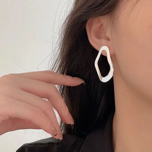 Detailed close-up of a minimalist hollow geometric silver earring worn by a model