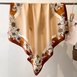 Detail of floral silk scarf hanging on hanger with warm beige and brown geometric patterns