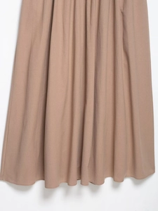 Detailed close-up of khaki maxi dress hem featuring elegant pleated fabric and soft draping