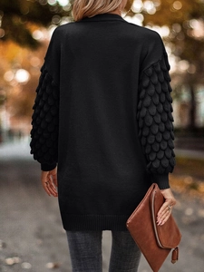 Detail of unique petal-textured knit sleeves on a black V-neck long-sleeve cardigan