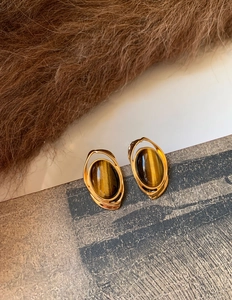 Dettaglio di orecchini vintage con occhio di tigre e cornice in metallo dorato a strati