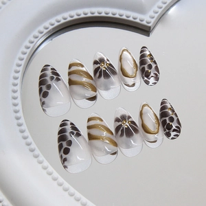 Unghie finte minimaliste leopardate e floreali con accenti dorati su uno specchio bianco