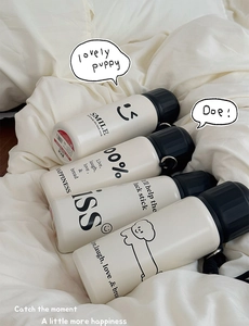 Detail of white matte stainless steel bottles with black caps and cute puppy illustrations
