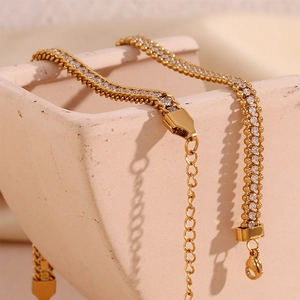 Detail of 18K gold-plated braided chain with zircon stone on a ceramic dish