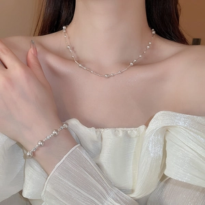 Detail of elegant French pearl necklace and bracelet set worn with a white silk top