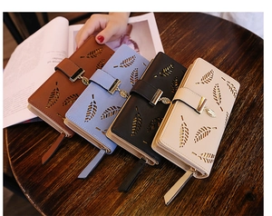 Macro detail of hollow leaf patterns and metallic charms on stylish long wallets