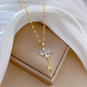 Luxury gold titanium necklace featuring a sparkling pink clover key pendant on box