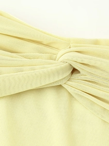 Detailed macro view of light yellow mesh fabric featuring a twisted knot front design