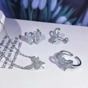 Macro detail of silver bow jewelry set including necklace earrings and ring with zircons