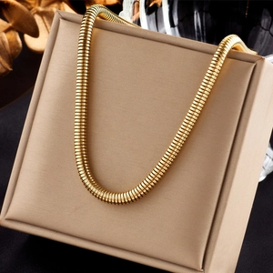 Detail of 18K gold-plated titanium steel snake chain on a beige jewelry display box