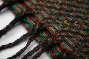 Close-up of multicolored herringbone weave texture and soft black fringe tassels